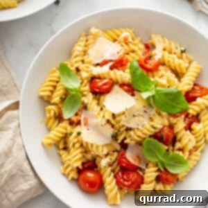 rotini pasta with cherry tomatoes and shaved parmesan in white bowl