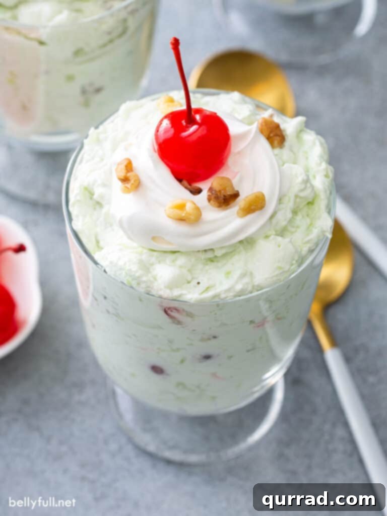 Pistachio Cloud Salad 3 Close-up of Watergate Salad in a glass cup with whipped cream and a Maraschino cherry on top.