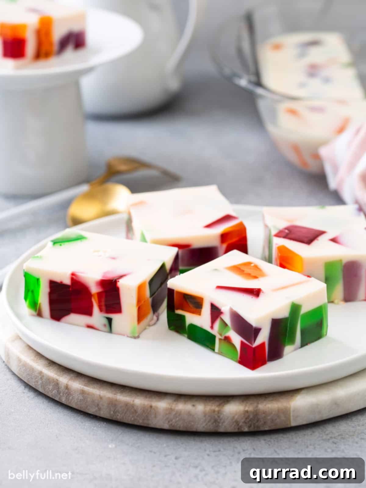 Squares of colorful Broken Glass Jello arranged on a white serving tray, ready for guests.