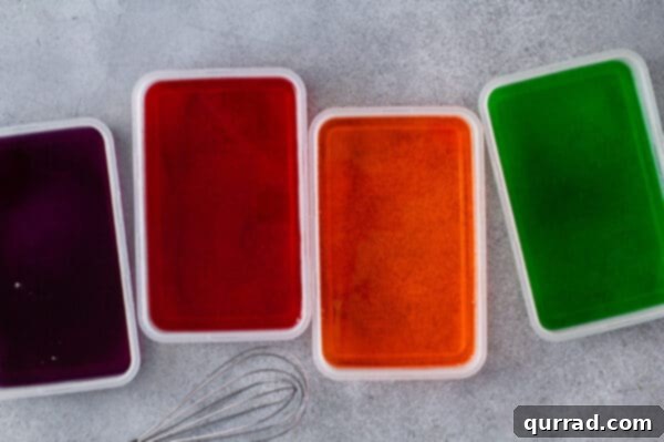 Plastic containers filled with orange, red, green, and purple Jello layers, chilled and ready.