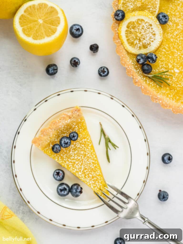 A single slice of lemon tart served on a white plate, beautifully garnished with fresh blueberries.