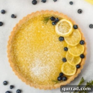 whole lemon tart garnished with lemon slices, blueberries, and powdered sugar