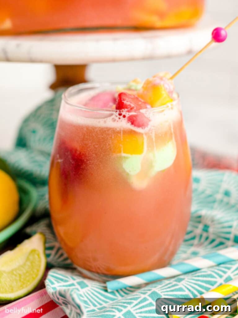 A tall glass filled with colorful sherbet punch, garnished with fresh fruit slices and a striped straw, ready to be enjoyed.