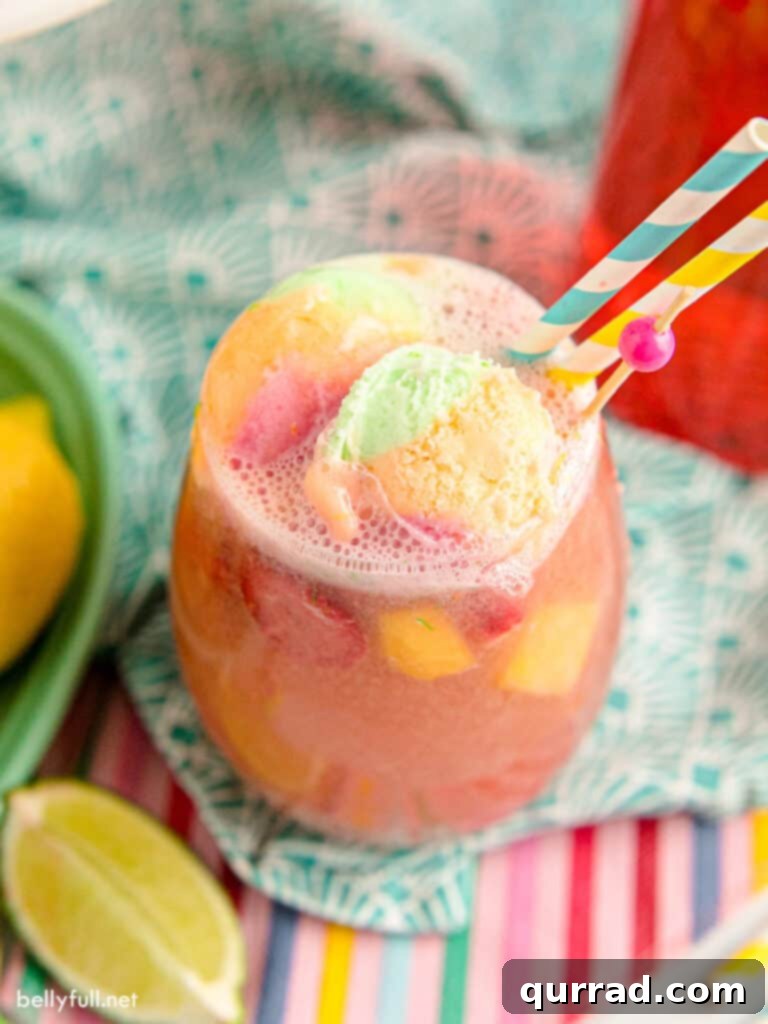 A refreshing glass of sherbet punch, adorned with a striped straw and fresh fruit, ready to be sipped.