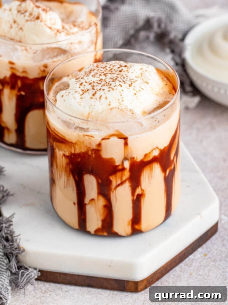 Classic Mudslide cocktail garnished with whipped cream and a sprinkle of cocoa powder, served in a stylish old-fashioned glass