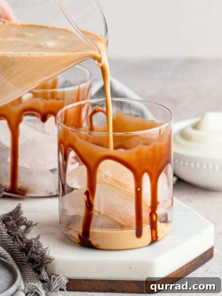 The process of pouring a freshly mixed Mudslide cocktail into an old-fashioned glass, prepared with chocolate syrup and ice