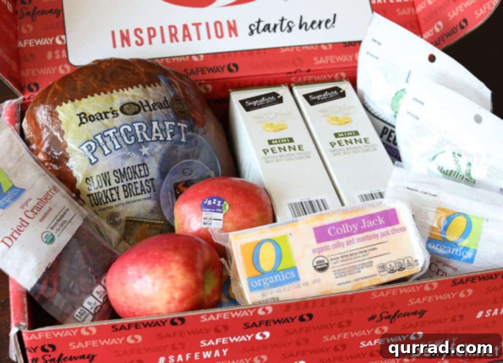 Crisp Apple Turkey Pasta Salad 4 An open Safeway grocery box filled with fresh ingredients for a pasta salad, including Boar's Head smoked turkey, Jazz apples, O Organics Colby-Jack cheese, dried cranberries, and mini penne pasta.
