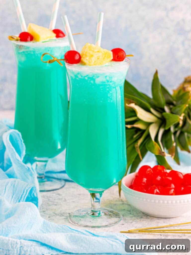 Blue Hawaii drink in hurricane glass with pineapple and cherry garnish