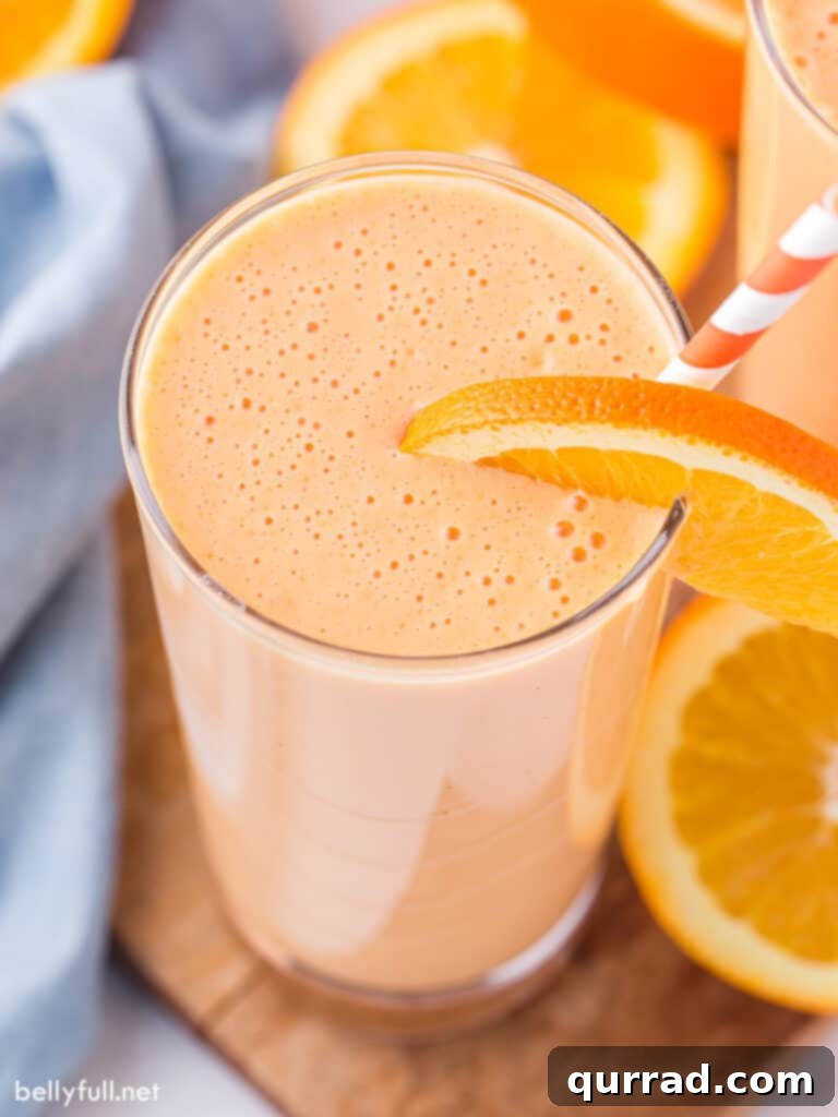 Creamy Orange Dream 2 Tall glass of Orange Julius garnished with an orange slice and a straw, showcasing its creamy texture