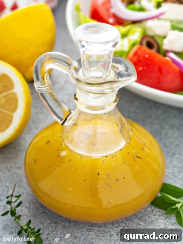 Freshly prepared Greek Salad Dressing in a clear glass carafe, ready for serving.