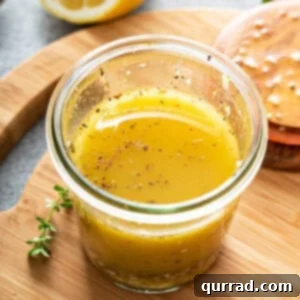Greek Salad Dressing in a glass jar resting on a cutting board.
