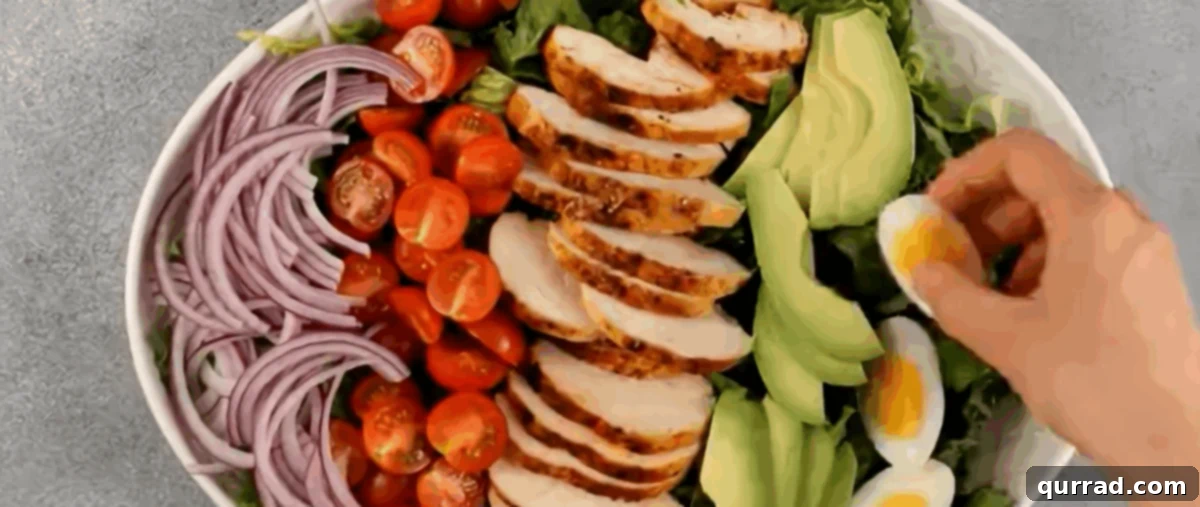 Legendary Cobb Salad 4 Preparing a Cobb salad. A bed of lettuce is laid out on a platter, ready for toppings.