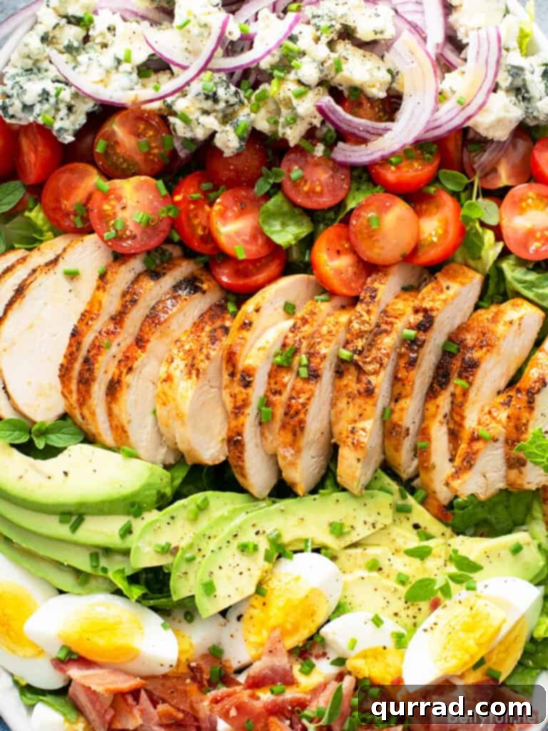Legendary Cobb Salad 7 Rows of perfectly cooked roasted chicken, creamy avocado, vibrant cherry tomatoes, and sliced hard-boiled eggs, neatly arranged.