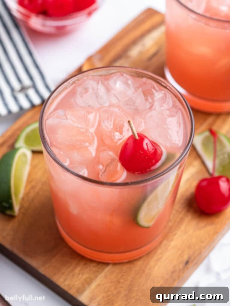 Crimson Tide Refresher 2 A crisp Sea Breeze Cocktail, garnished with a bright cherry, served in a highball glass on a warm day.