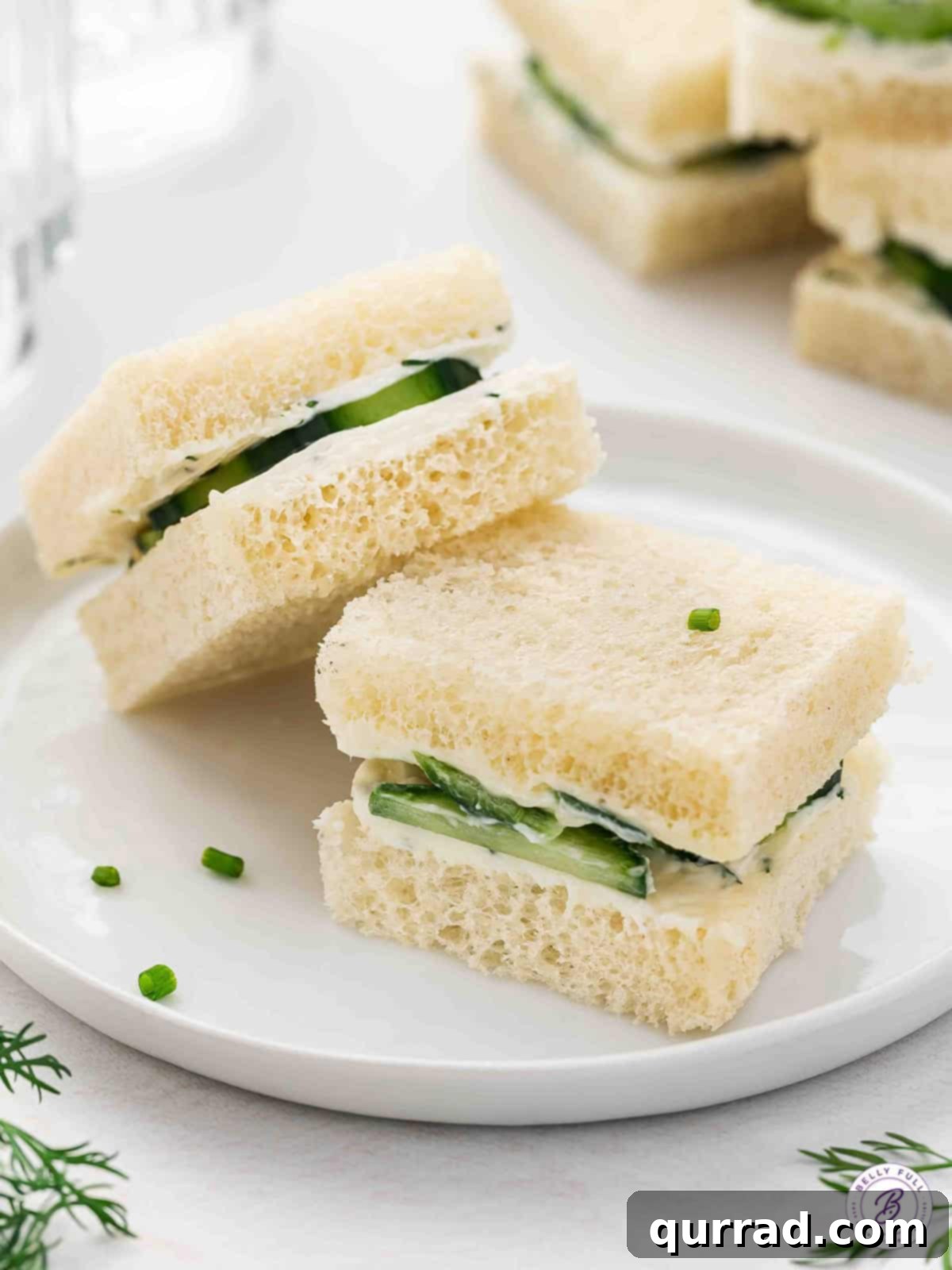 Two perfectly prepared cucumber tea sandwiches resting elegantly on a small white plate.