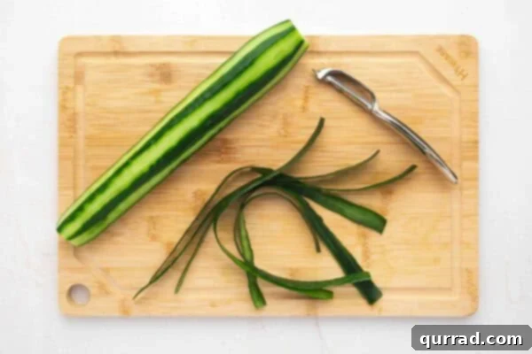 An English cucumber being expertly peeled in preparation for slicing.