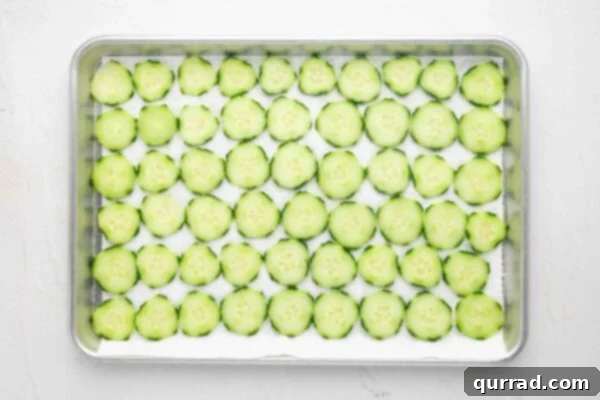Thinly sliced cucumber rounds resting on paper towels, lightly salted to draw out moisture.