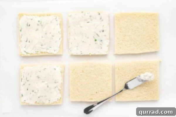 Squares of white bread meticulously spread with the homemade herbed cream cheese mixture.