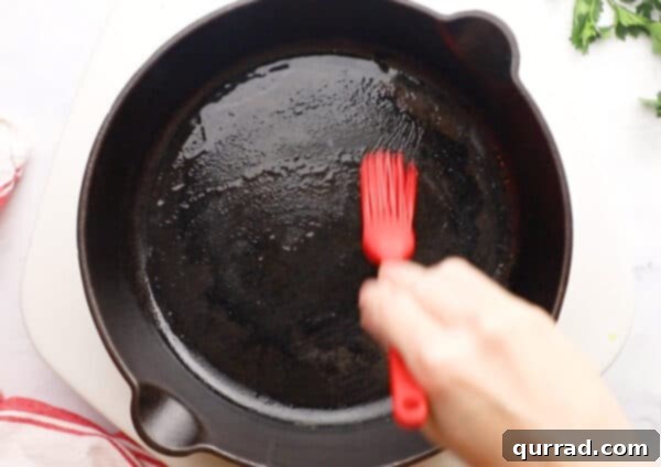 Pillowy Indian Flatbread 12 A basting brush applying olive oil to a hot cast iron skillet