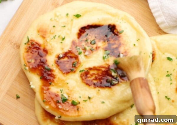 Pillowy Indian Flatbread 15 Melted garlic butter being brushed onto a warm piece of naan bread with a basting brush