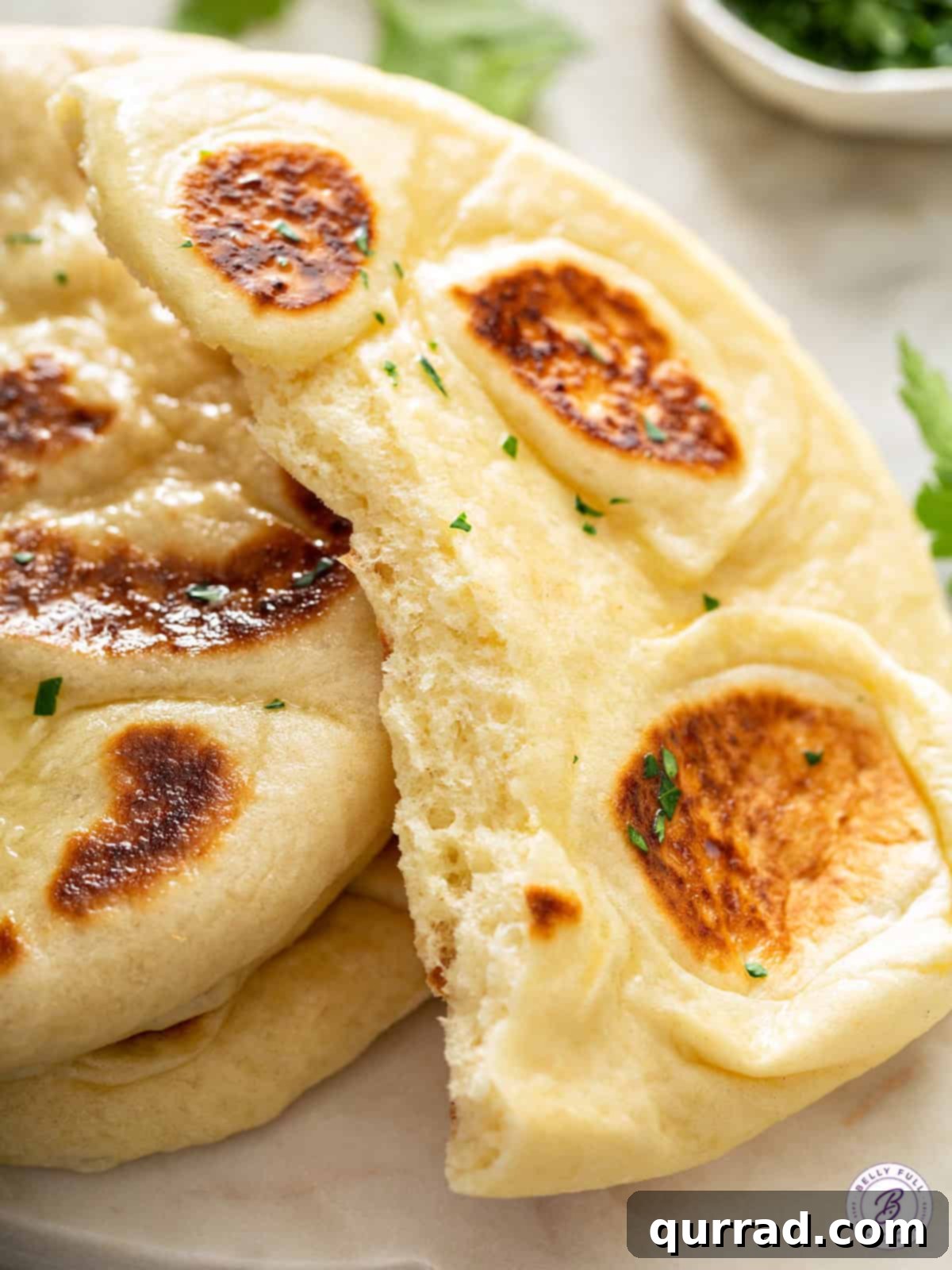 Soft and Airy Naan Interior Freshly cooked naan bread split in half, revealing its soft, airy, and textured interior