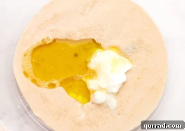 Pillowy Indian Flatbread 3 Yeast mixture combined with egg, oil, yogurt, and salt in a glass bowl