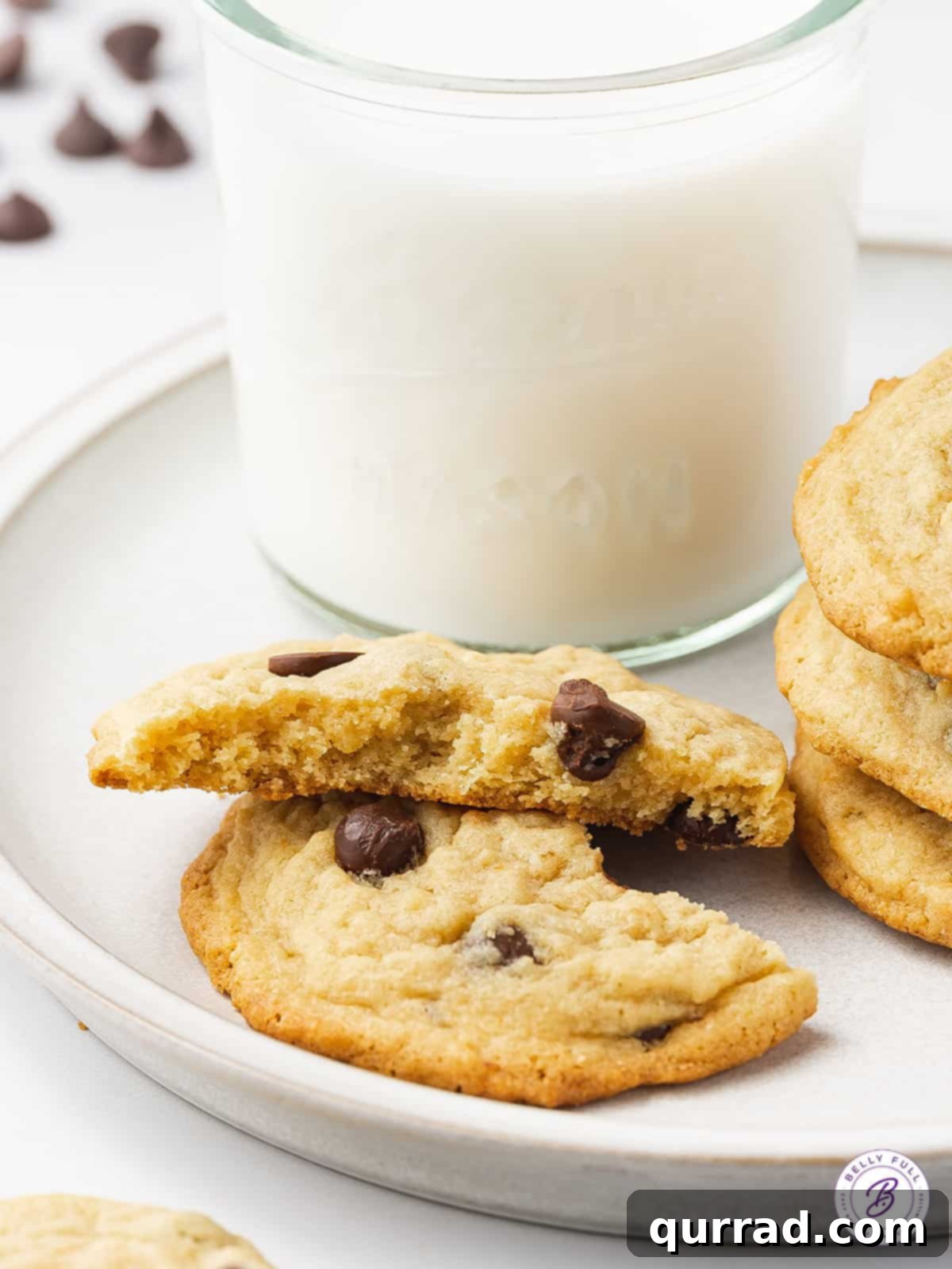 Soft and Chewy Chocolate Chip Pudding Cookies 5 A chocolate chip pudding cookie broken in half, revealing its soft, chewy interior with melted chocolate, next to a refreshing glass of milk.