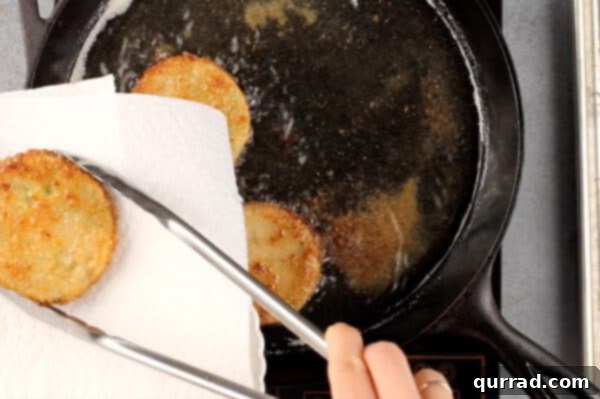 fried green tomatoes being placed on paper towel to drain