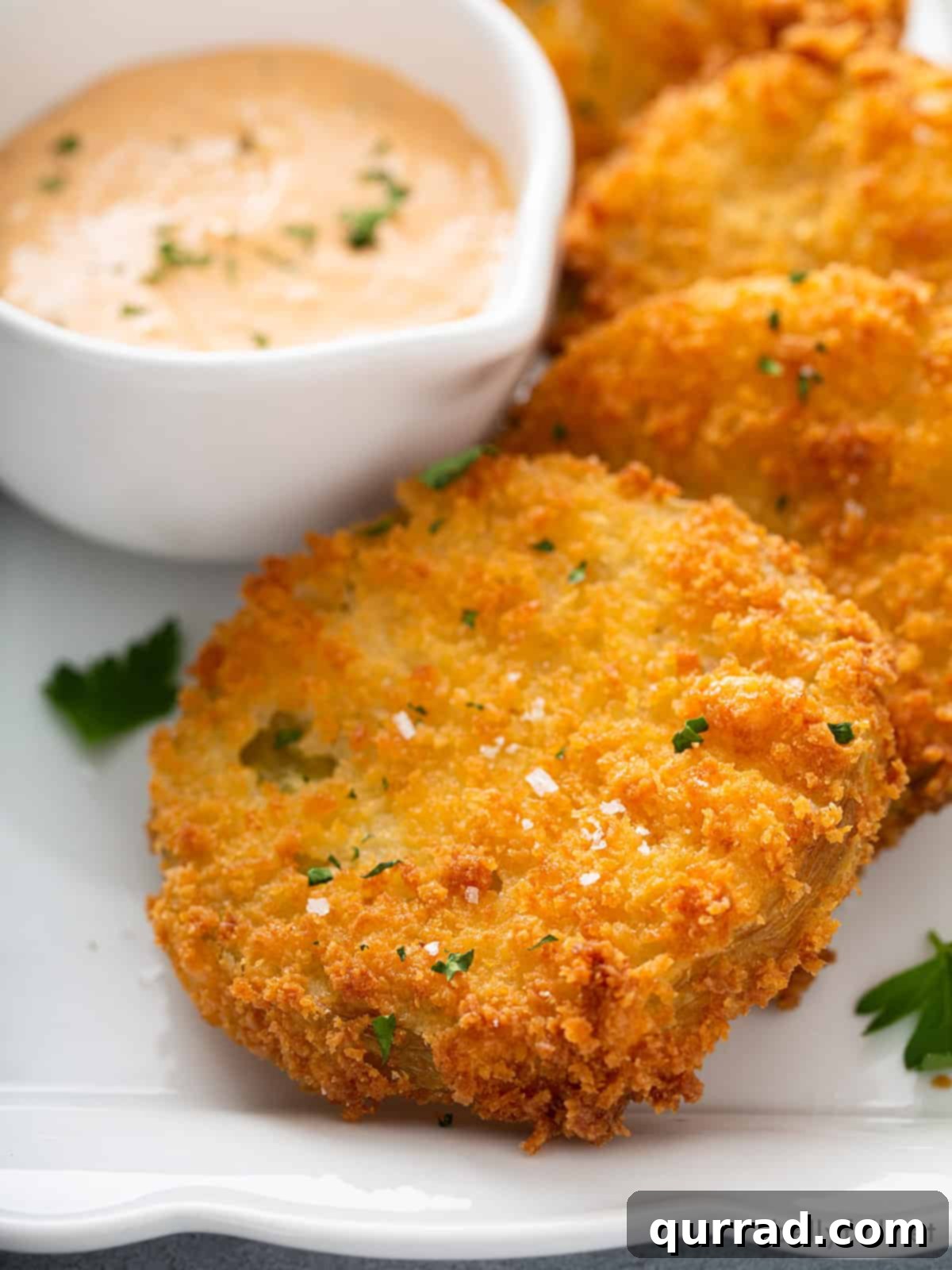 close up image of a single breaded fried tomato on a white plate