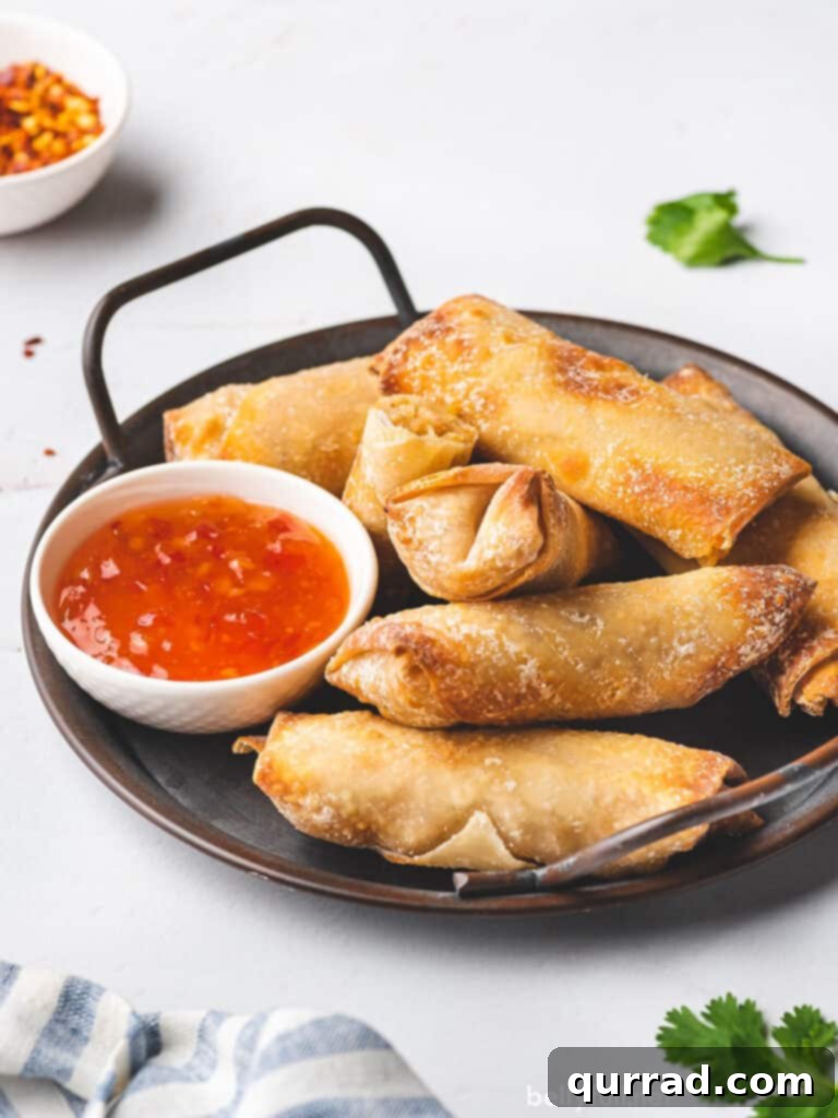 Crispy Air Fryer Egg Rolls 3 air fryer egg rolls on serving platter with sweet chili sauce