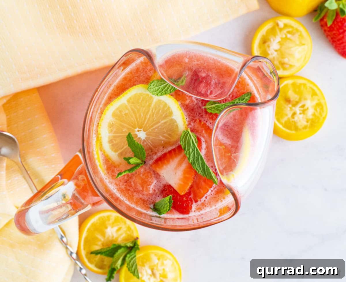 Vibrant Strawberry Lemonade 5 A large glass pitcher filled with vibrant pink strawberry lemonade, ready to be served, evokes a sense of refreshing summer indulgence.