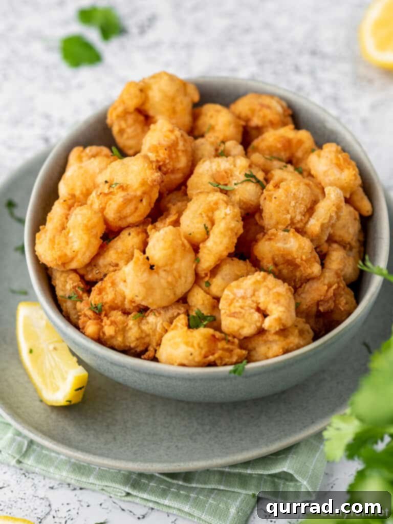 Crunchy Shrimp Poppers 8 A full bowl of golden, crispy popcorn shrimp garnished with a lemon wedge, ready to be served.