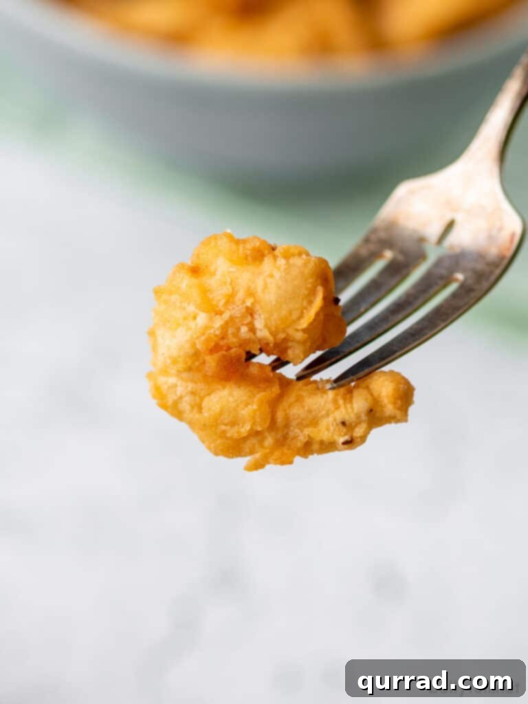 Crunchy Shrimp Poppers 9 Close-up of a perfectly breaded fried shrimp on a fork, highlighting its golden, crispy texture.