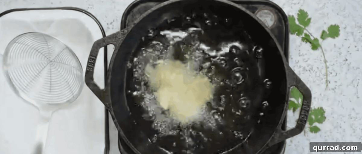 Crunchy Shrimp Poppers 7 Deep frying several pieces of breaded popcorn shrimp in a pot of hot oil until golden brown.