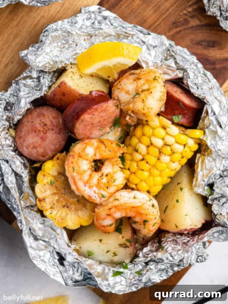Garlic Butter Shrimp Boil Foil Packs 2 Overhead close-up view of a perfectly cooked shrimp boil foil packet, showcasing shrimp, sausage, corn, and potatoes bursting with flavor