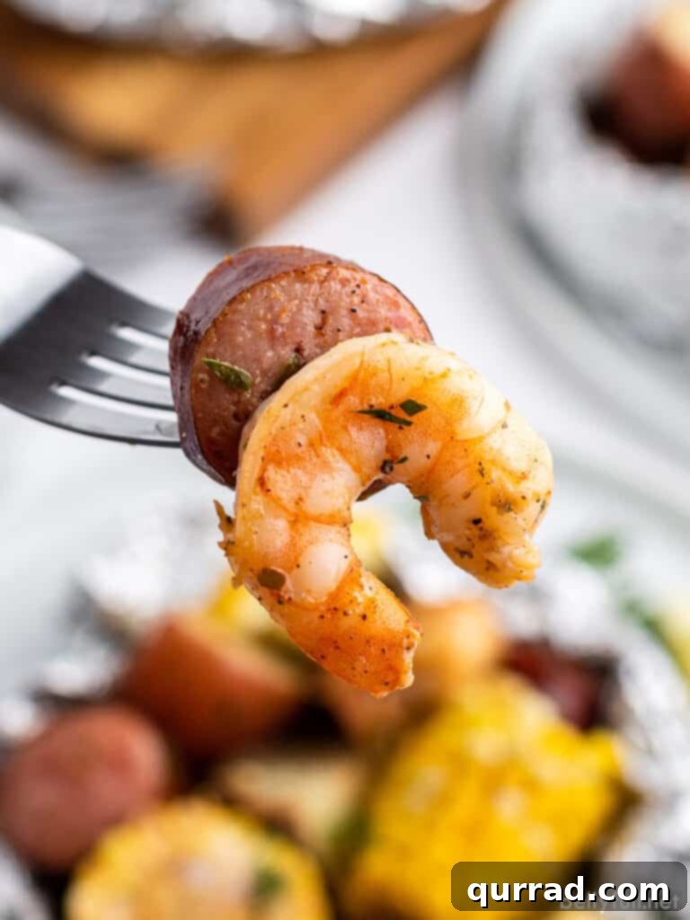 Garlic Butter Shrimp Boil Foil Packs 4 Close-up shot of smoked sausage and shrimp on a fork, showing the delicious textures
