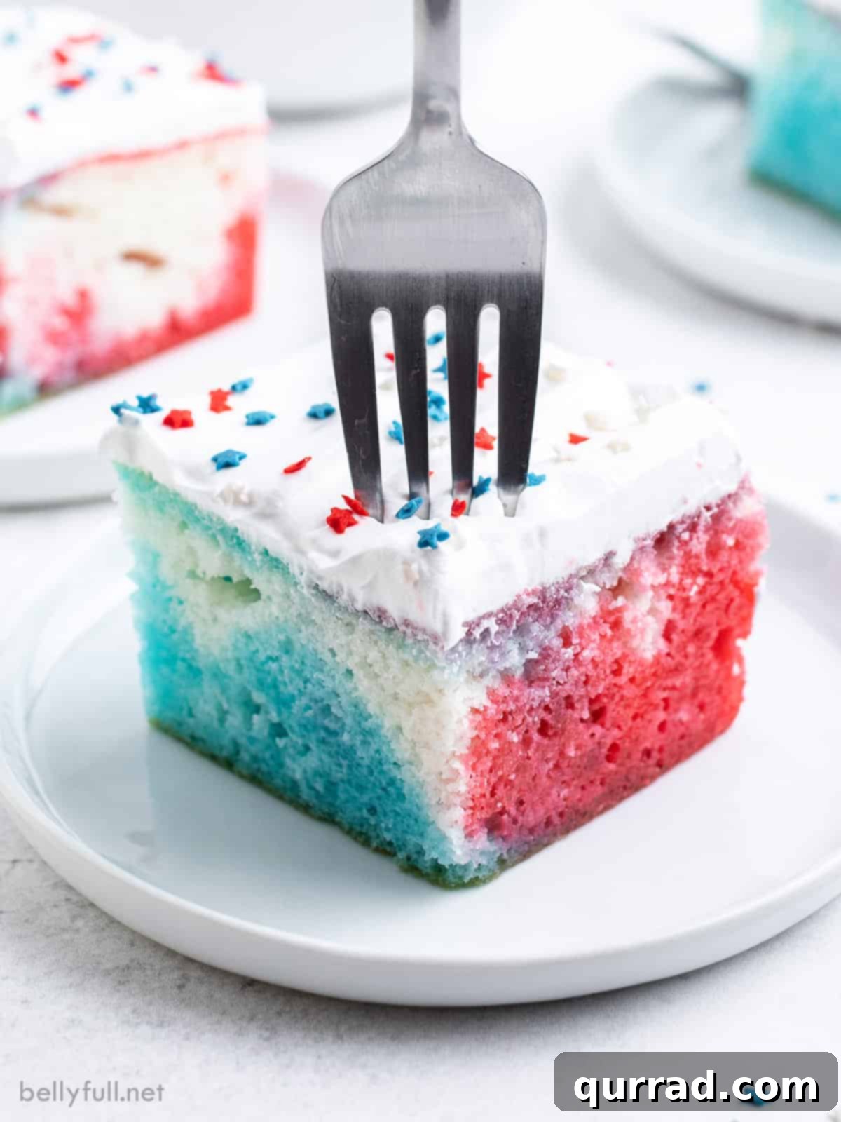 Festive Flag Poke Cake 5 A delectable slice of patriotic poke cake, revealing its moist texture and vibrant red and blue gelatin stripes, ready to be enjoyed with a fork. This Jell-O infused cake is a perfect summer dessert.