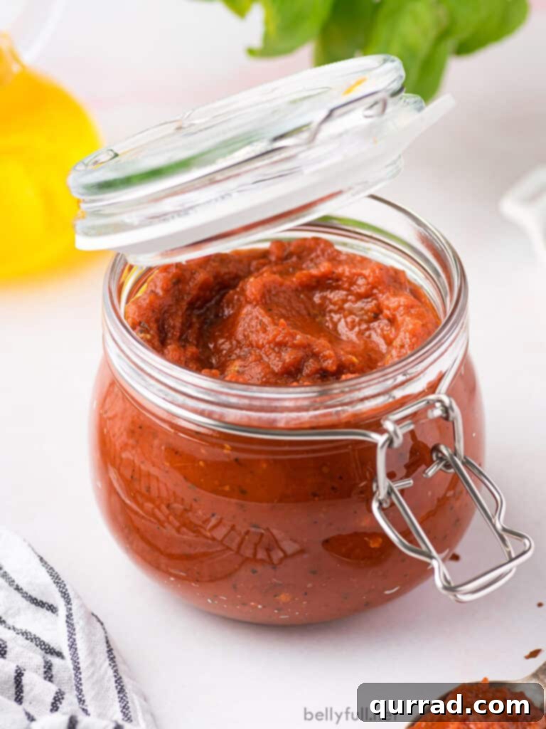 Homemade pizza sauce in a glass jar with a lid, showcasing its rich, thick consistency.