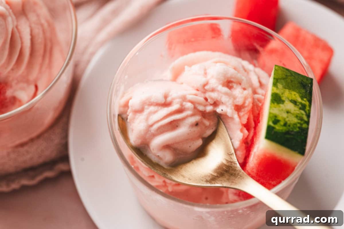 A spoon digging into a dish of fluffy, pink watermelon dole whip, showing its creamy texture.