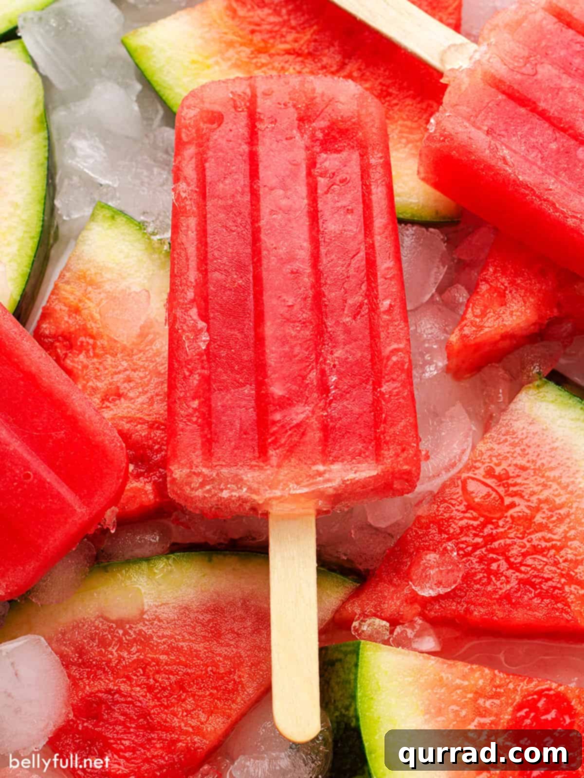 Refreshing Watermelon Ice Pops 2 A homemade watermelon popsicle on top of frozen watermelon slices, showcasing its vibrant red color and refreshing appeal.