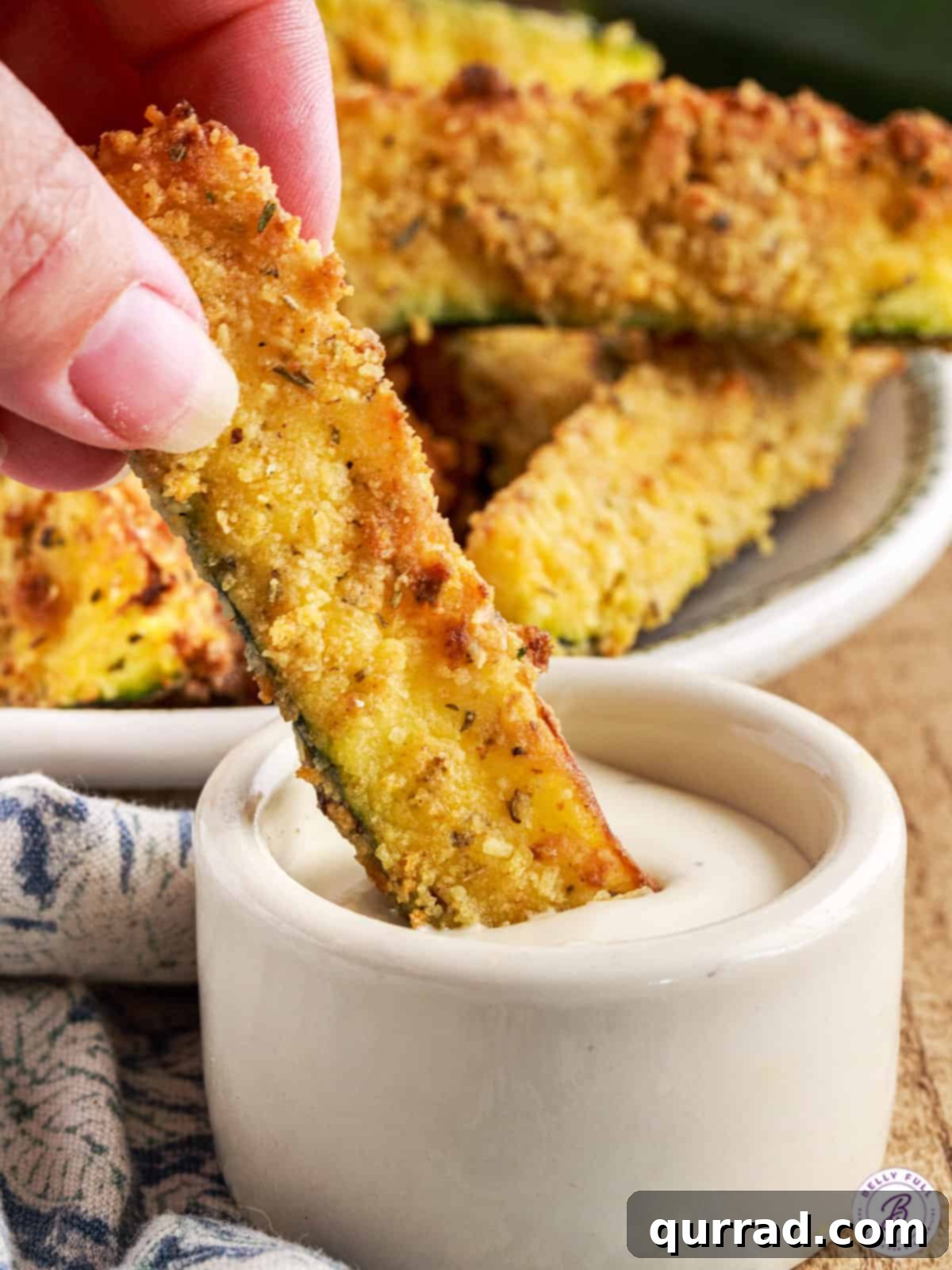 Crispy Air Fryer Zucchini Fries 4 hand dipping breaded zucchini wedge in ranch dressing