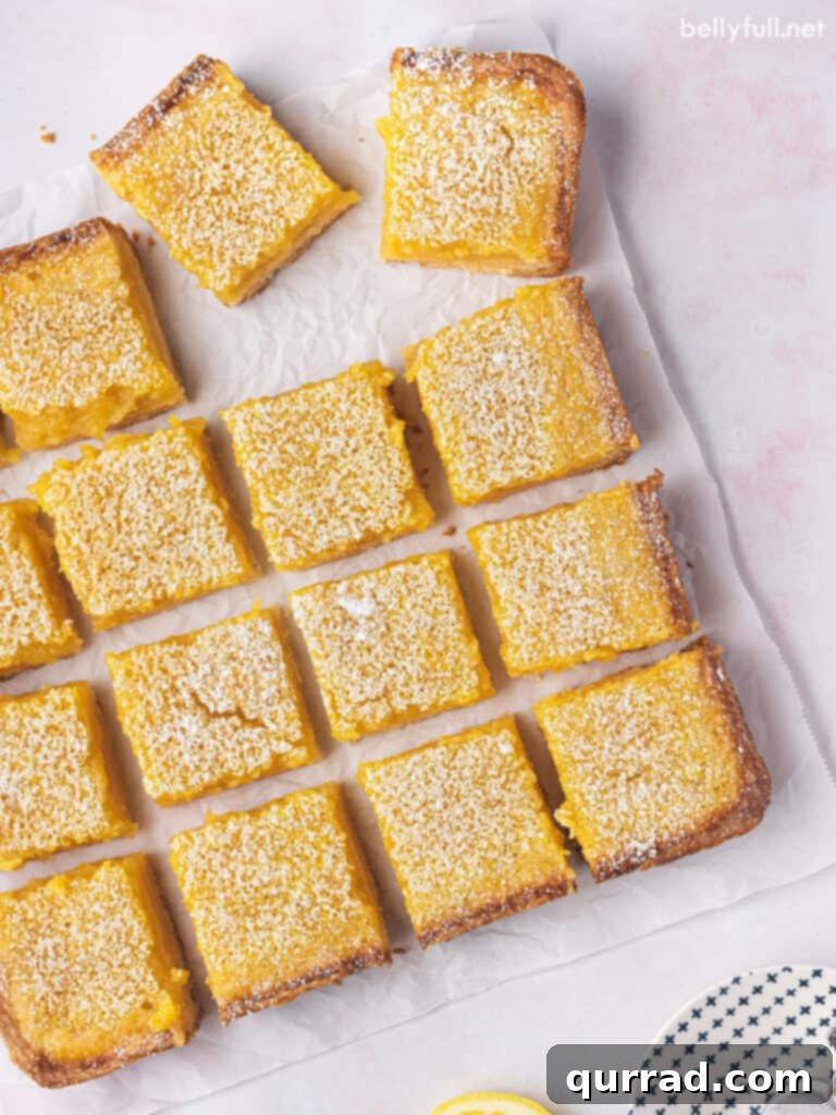 Zesty Lemon Bars 3 overhead cut lemon bar squares on parchment paper