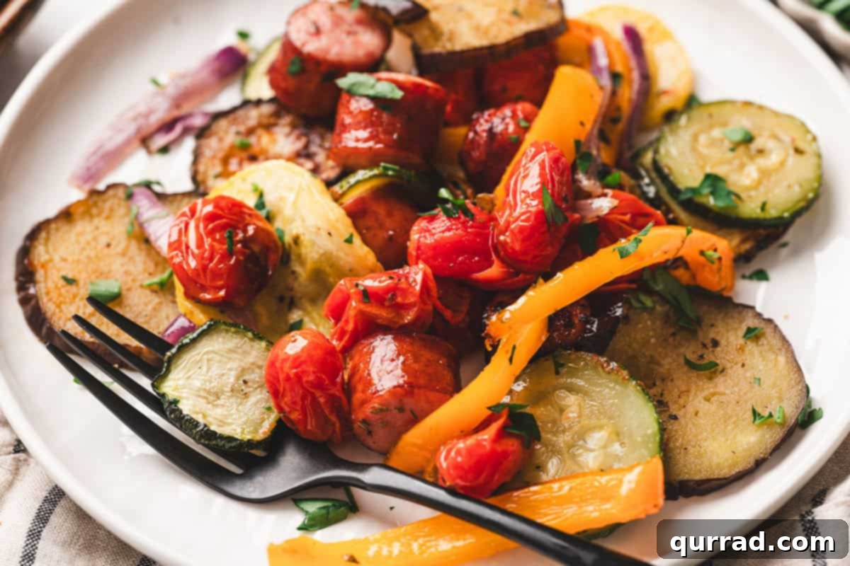 A sheet pan of freshly roasted ratatouille with tender vegetables and slightly charred sausage