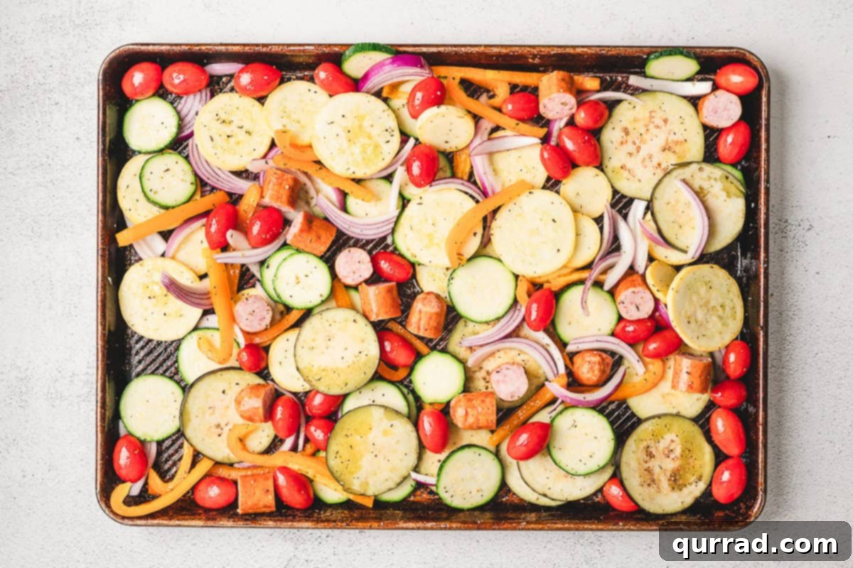 Pouring a whisked olive oil and spice dressing over the vegetables and sausage on the sheet pan