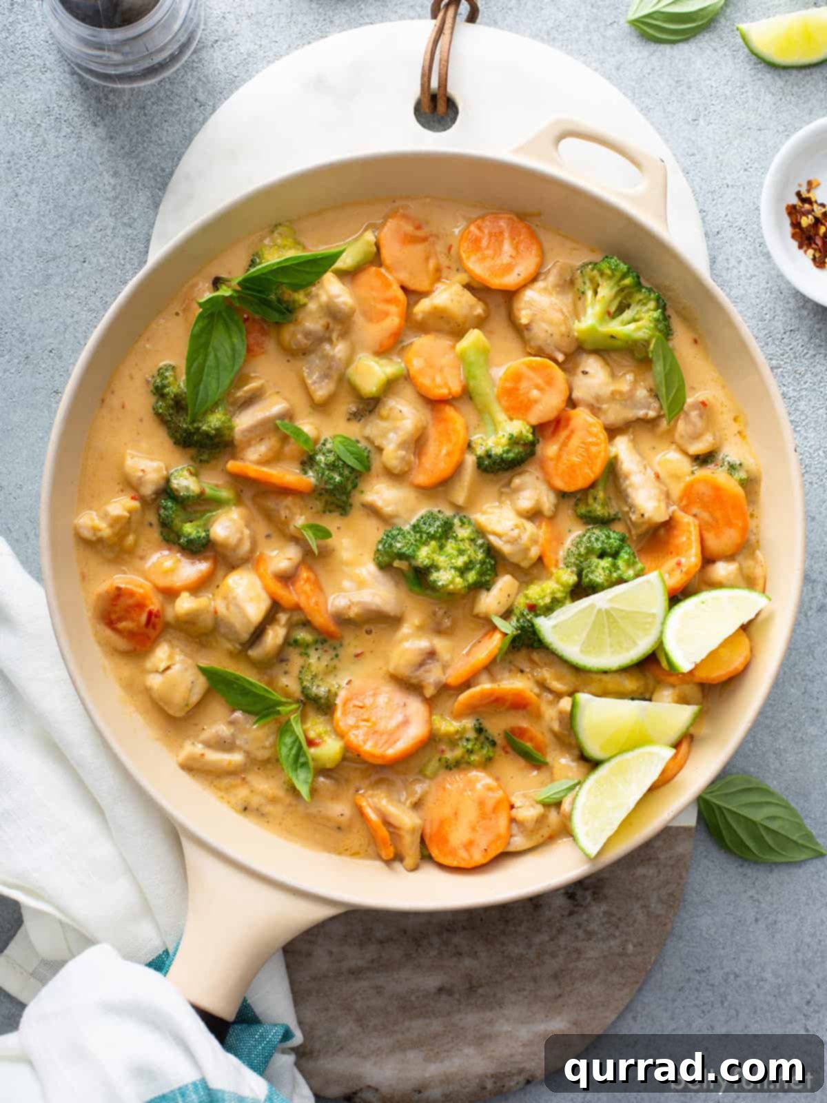 Dreamy Thai Coconut Chicken 3 A skillet filled with succulent chicken pieces, vibrant broccoli, and sliced carrots bathed in a rich, creamy coconut sauce.