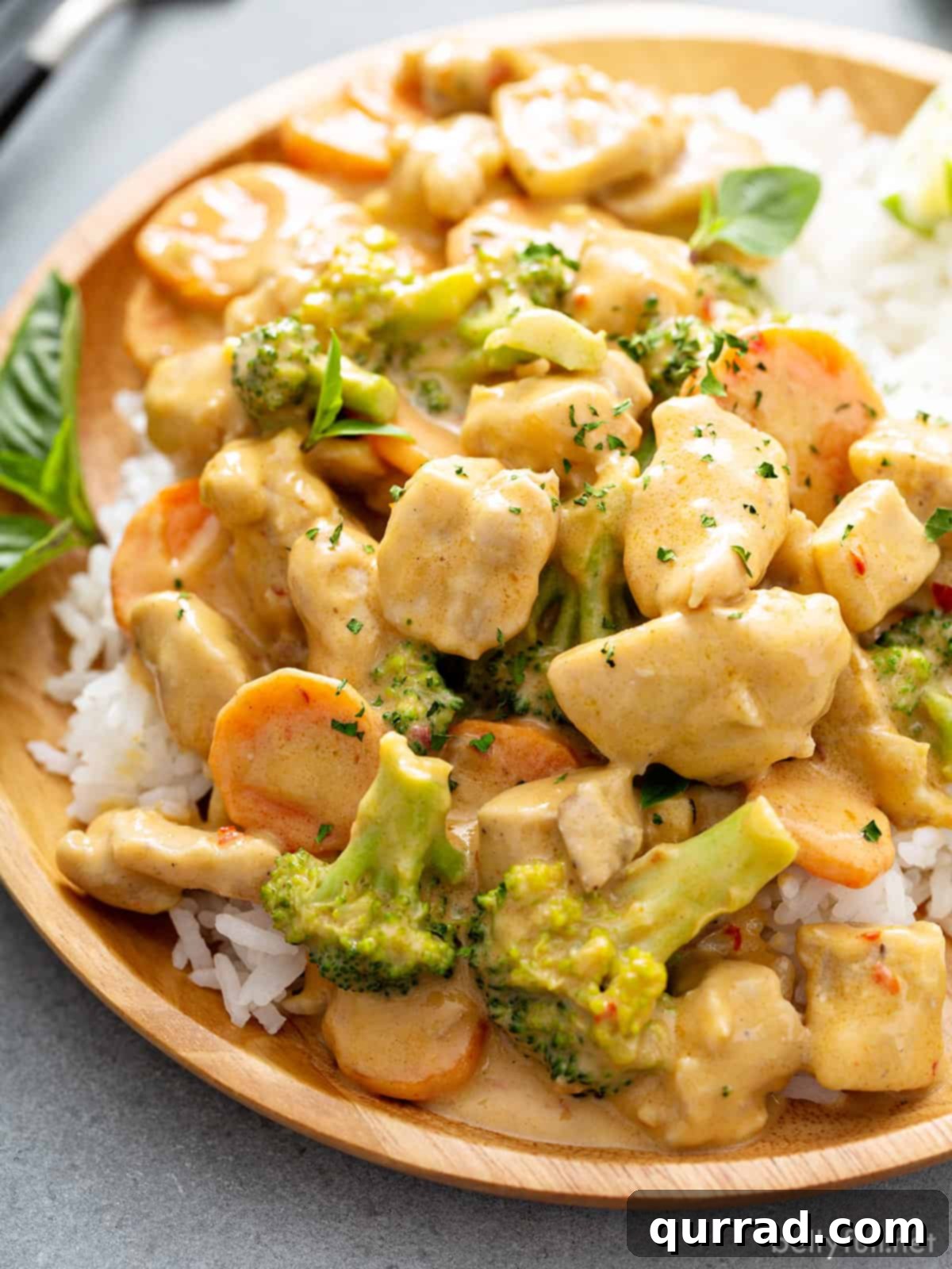 Dreamy Thai Coconut Chicken 4 A beautifully plated serving of Thai coconut chicken over a bed of white rice, garnished with fresh Thai basil.