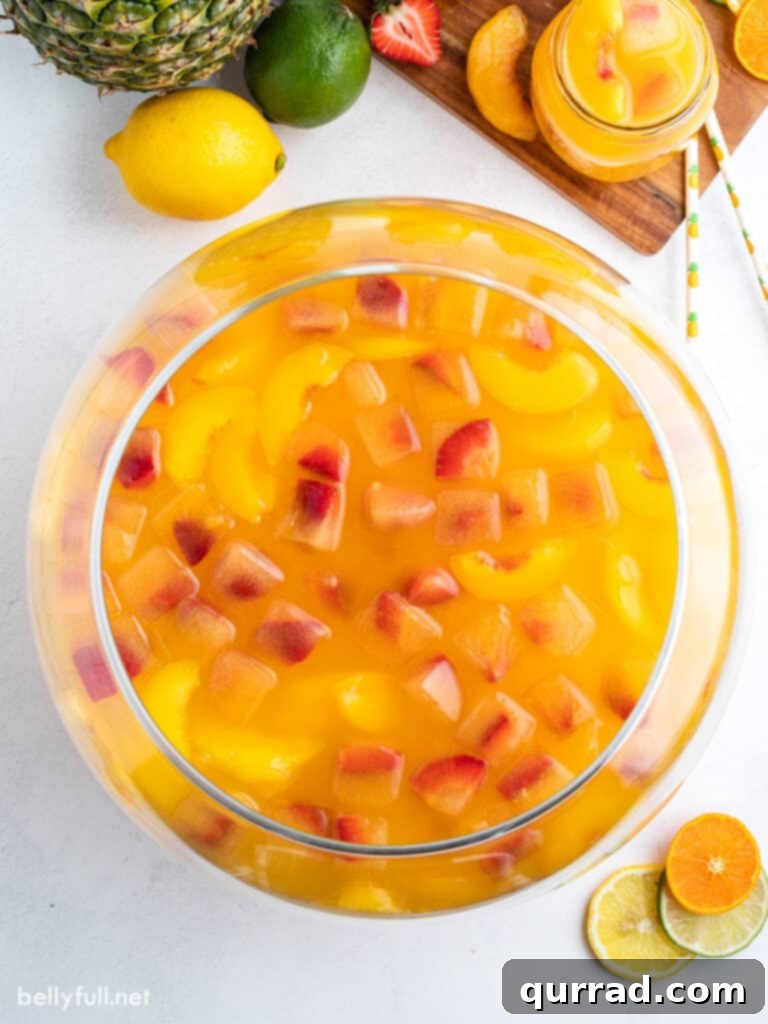 Sunburst Fruit Medley 2 Overhead view of a clear punch bowl generously filled with vibrant fruit punch, adorned with strawberry fruit ice cubes.