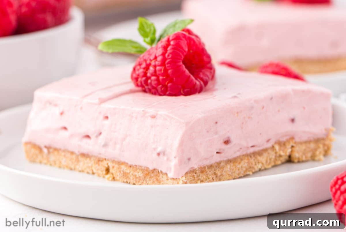 A no-bake raspberry cheesecake bar topped with fresh raspberries on a white plate