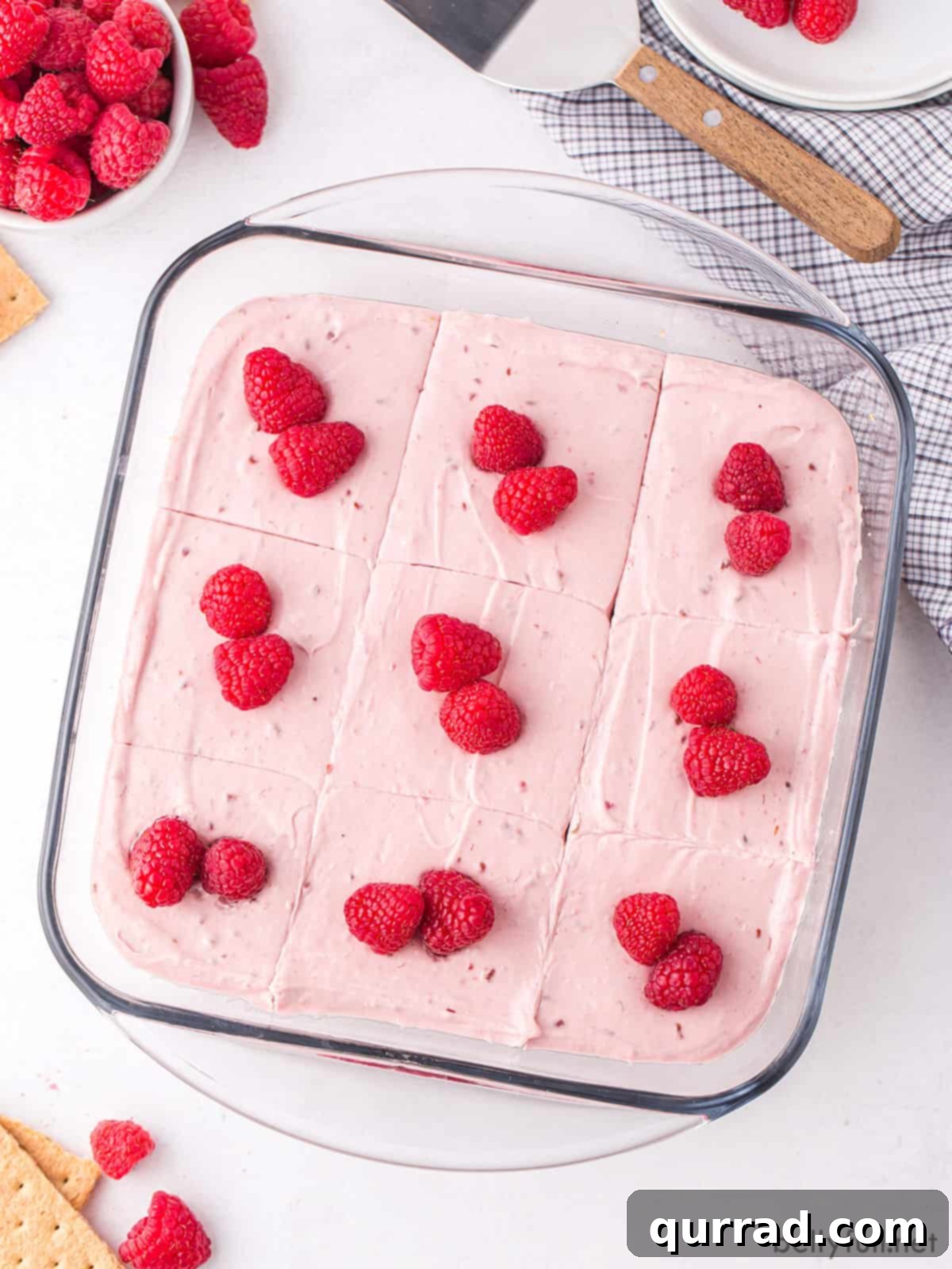 No-bake raspberry cheesecake bars topped with fresh raspberries in a baking dish