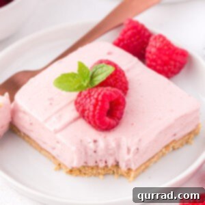 Raspberry no bake cheesecake bar on a plate with a bite on a spoon